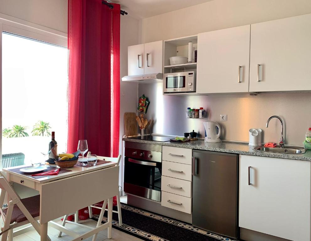 uma cozinha com armários brancos, uma mesa e um lavatório em Vivienda Gorrión em Morro del Jable