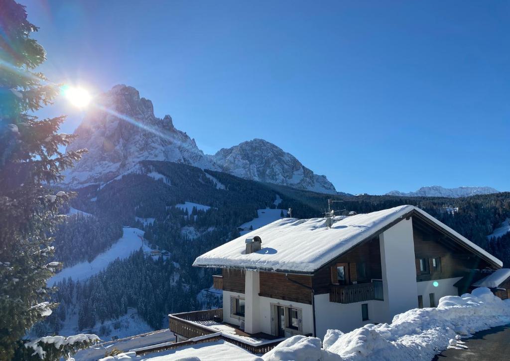 a house with snow on the roof with a mountain at Pension Dolomieu in Santa Cristina in Val Gardena