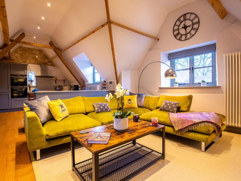 ein Wohnzimmer mit einem gelben Sofa und einem Tisch in der Unterkunft The Hayloft in Winchcombe