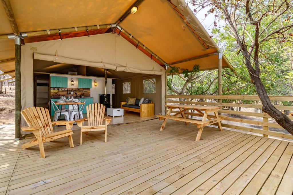 a wooden deck with a tent with a table and chairs at AfriCamps Hoedspruit in Hoedspruit