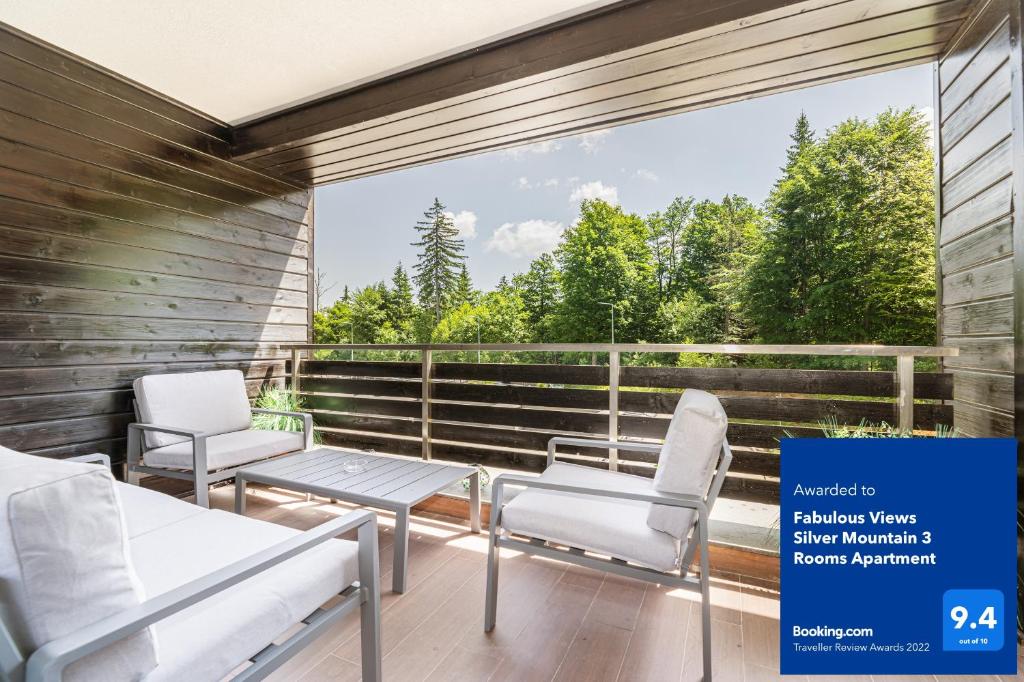 a balcony with two chairs and a table and a view of trees at Fabulous Views Silver Mountain 3 Rooms Apartment in Poiana Brasov