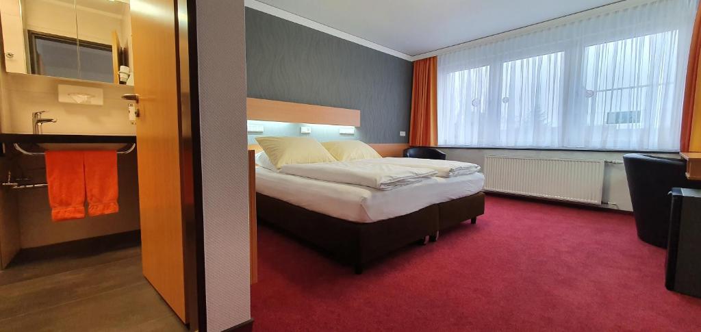 a hotel room with a bed and a bathroom at Akzent Hotel Oberhausen in Oberhausen