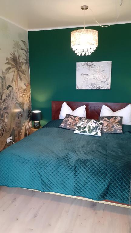 - une chambre avec un grand lit et un mur vert dans l'établissement Ferienhäuser Geiseltal, à Mücheln