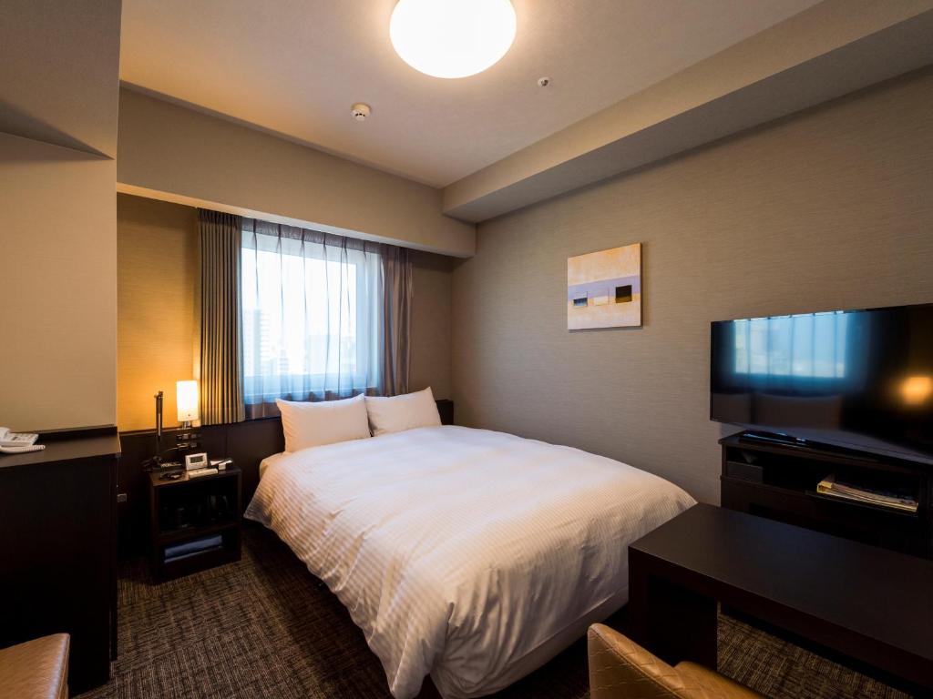 a hotel room with a bed and a flat screen tv at Hotel Route-Inn Grand Tokyo Asakusabashi in Tokyo