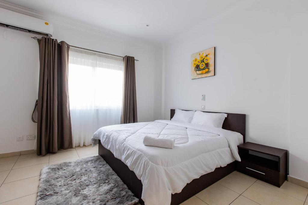 - une chambre avec un grand lit et une fenêtre dans l'établissement Accra Fine Suites - Holi Flats Airport Residential, à Accra