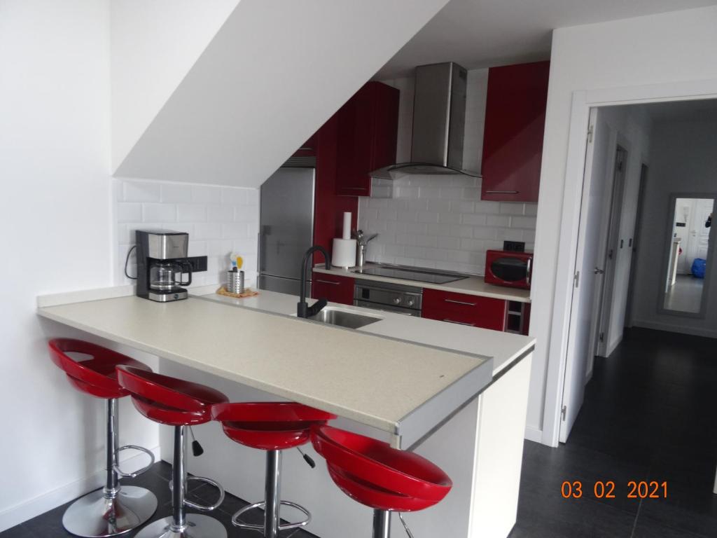 una cocina con taburetes rojos en un mostrador en Apartamentos Casa Mucha, en Combarro