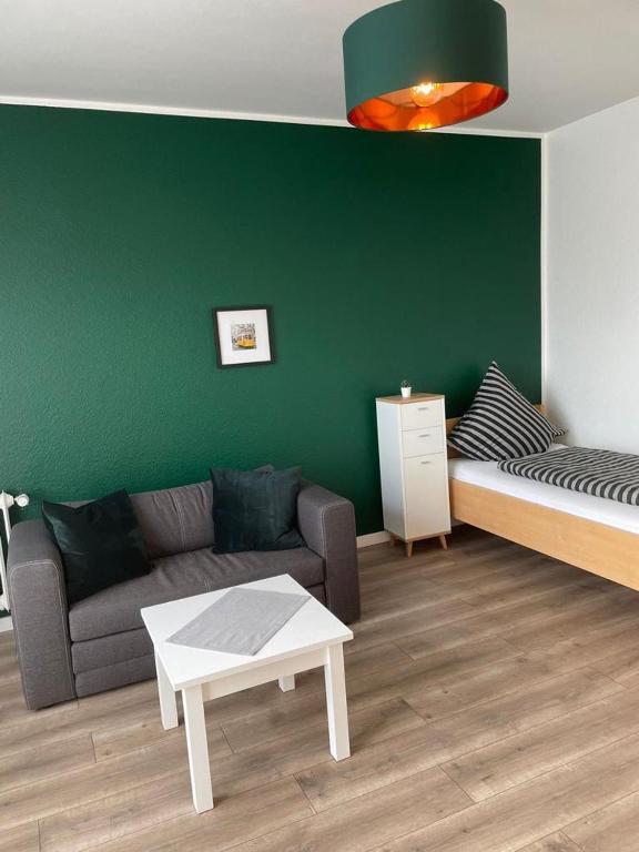 a living room with a couch and a green wall at Cityapartment in Stadtlohn