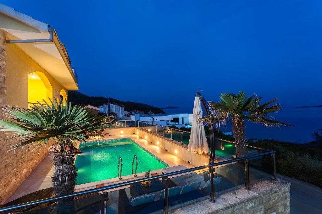 einen Swimmingpool mit Palmen auf einem Balkon in der Nacht in der Unterkunft Villa Kruna in Potirna