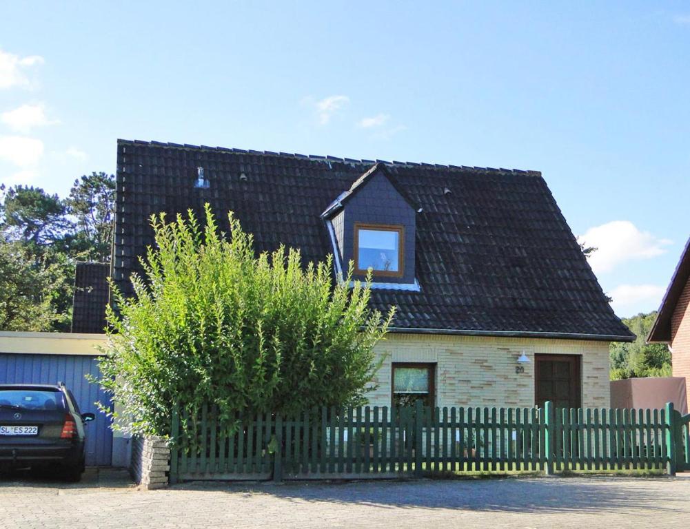 a house with a black roof and a fence at Skrey's To Hus in Kappeln