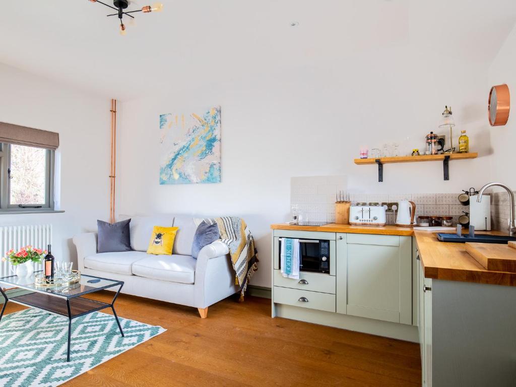 a kitchen and living room with a couch and a table at Paddock Cottage in Winchcombe