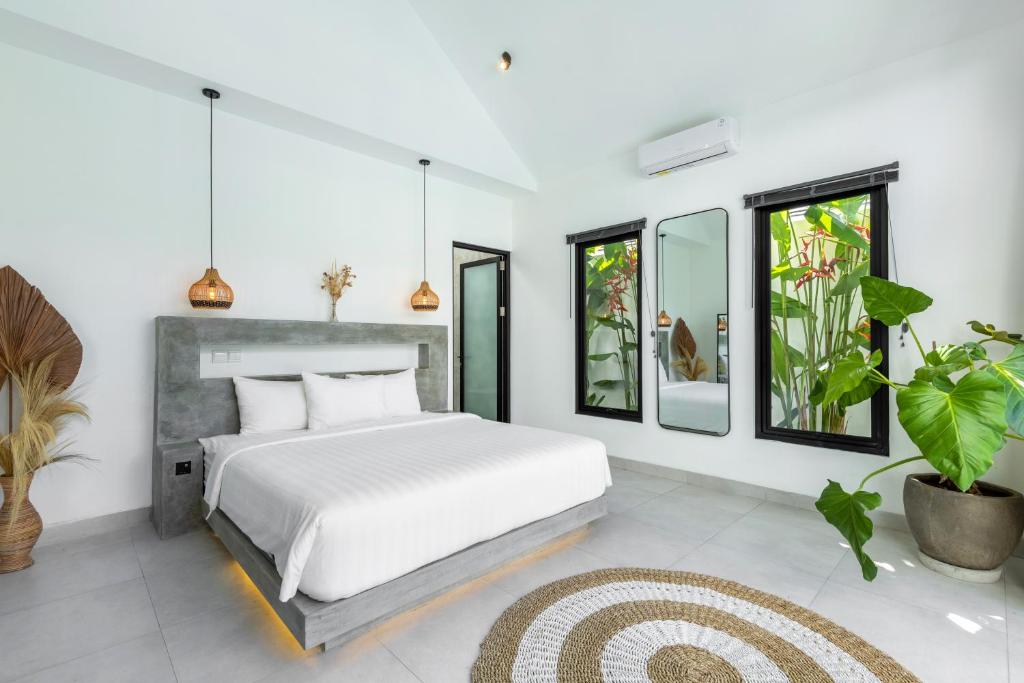 a bedroom with a white bed and some plants at Villa Dutch in Canggu