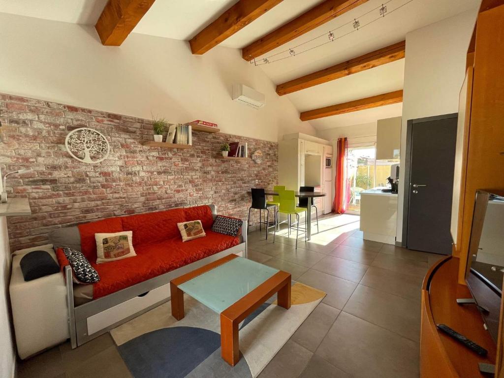 a living room with a red couch and a brick wall at Maison F2, neuve au calme avec jardinet in La Crau