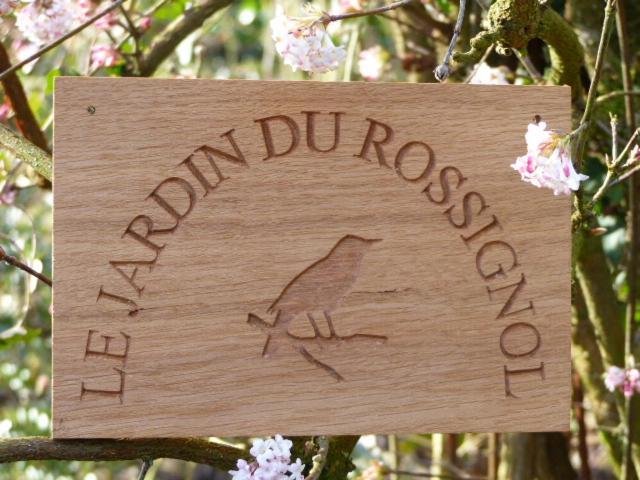 a wooden sign with a bird written on it at LE JARDIN DU ROSSIGNOL in Willeman