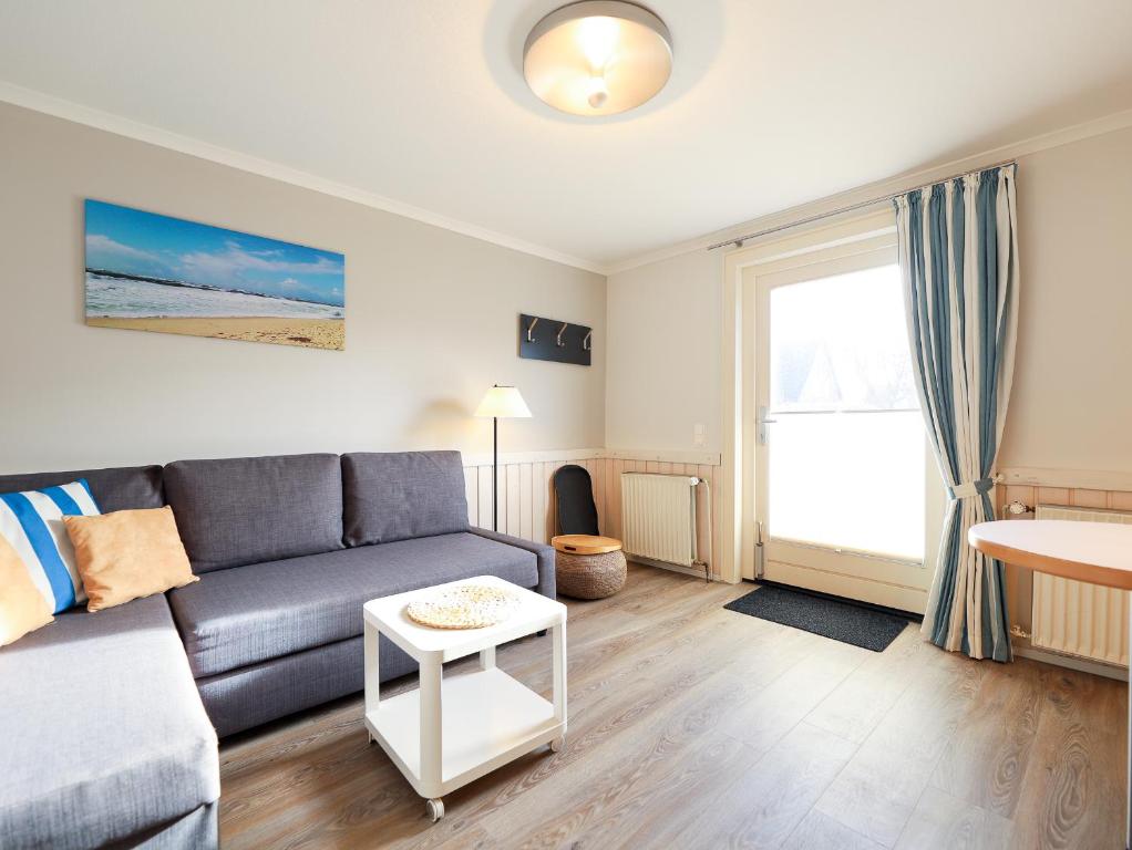 uma sala de estar com um sofá e uma mesa em Appartement Riterspöör 24 em Westerland