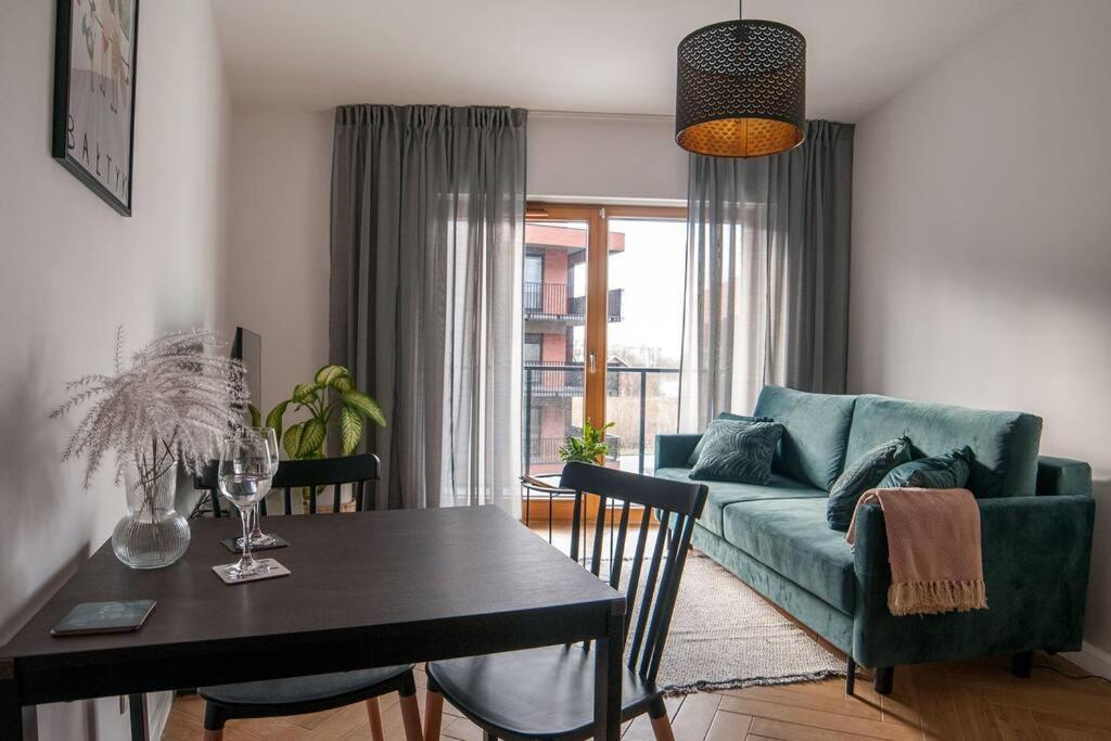 un soggiorno con tavolo e divano verde di NAP Apartments Nadmotławie Bałtyk a Danzica
