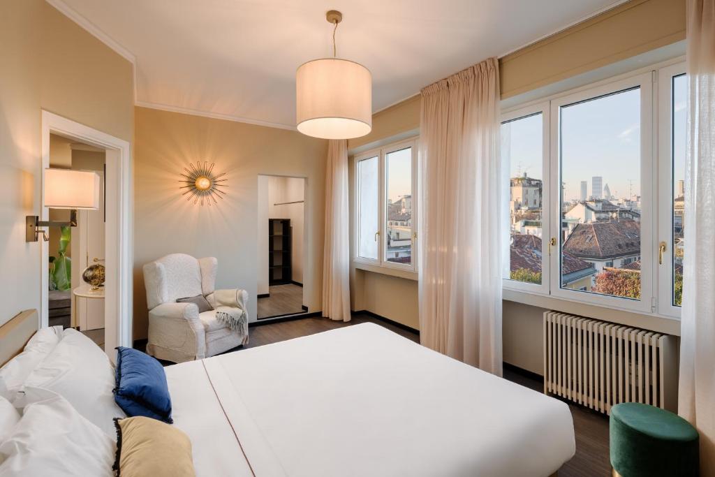 una camera da letto con un grande letto bianco e finestre di Hotel Mentana, by R Collection Hotels a Milano