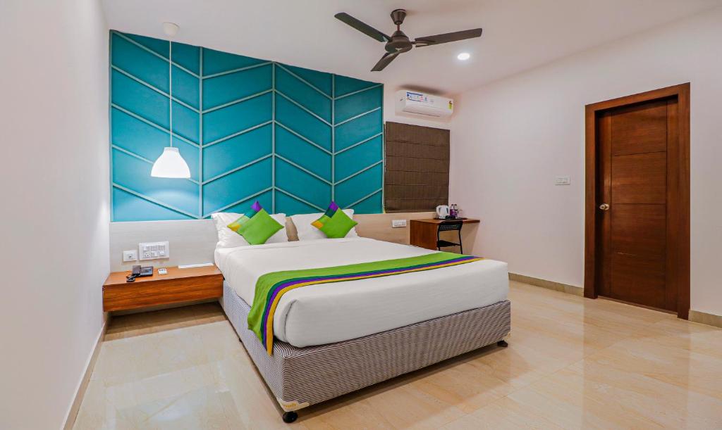 une chambre avec un grand lit et une tête de lit bleue dans l'établissement Treebo Trend YC Grand Boutique, Electronic City, à Bangalore
