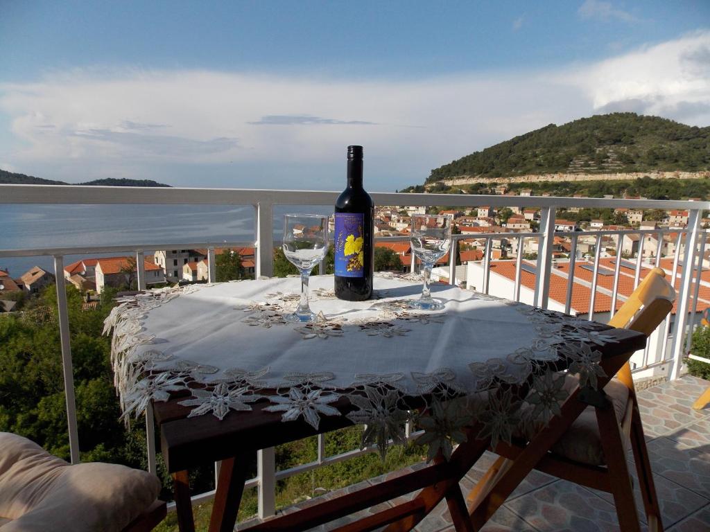 Una botella de vino sentada en una mesa en un balcón en Apartment Pečarević - a holiday with a stunning view, en Vis