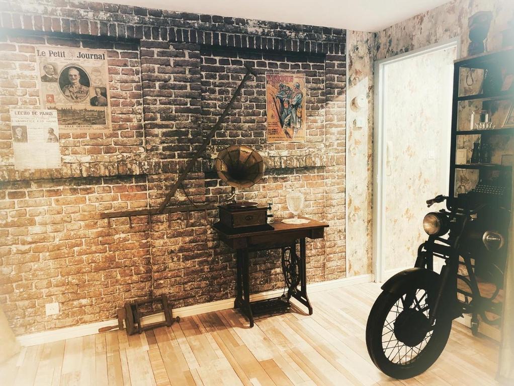 Cette chambre est dotée d'un mur en briques et d'une table avec un vélo. dans l'établissement Le rétro, à Verdun-sur-Meuse