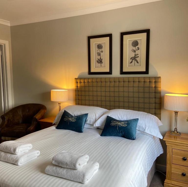 a bedroom with a large white bed with blue pillows at Balnearn House in Aberfeldy