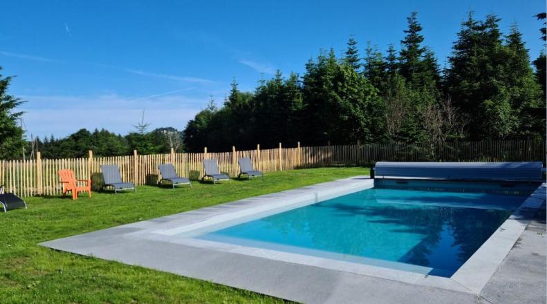 a swimming pool with lounge chairs and a fence at La Maison des Champs in Saint-Agrève