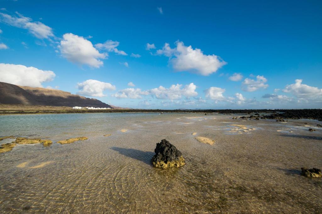 a rock in the water on a beach at Tranquilo y Acogedor Apartamento in Órzola