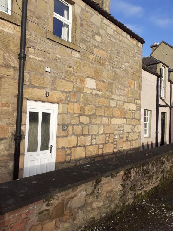 a stone building with a white door on it at Bees Townhouse- Cupar in Cupar