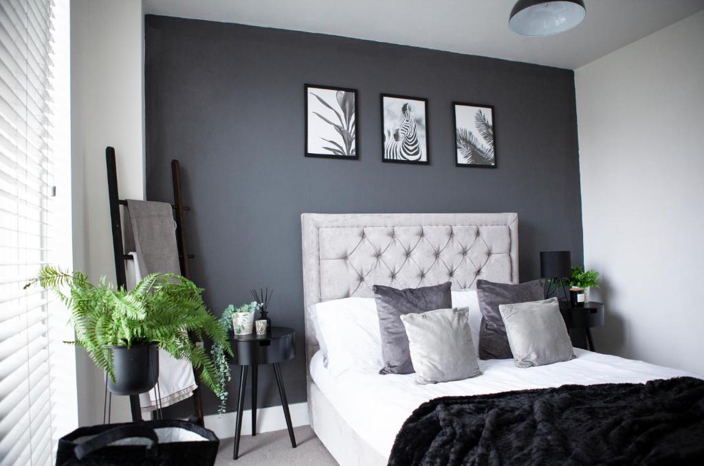 a bedroom with a white bed with three pictures on the wall at Modern city centre apartment roof garden in Manchester