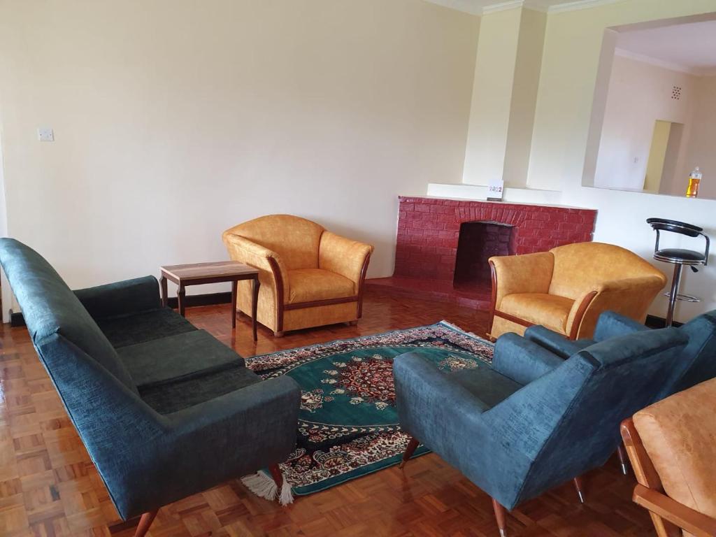 sala de estar con sillas azules y chimenea en Thayo Place, en Nyeri