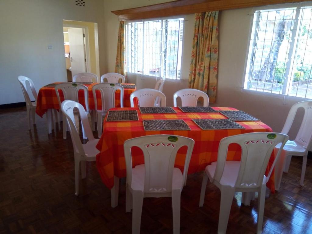 a dining room with a table and white chairs at Thayo Place in Nyeri