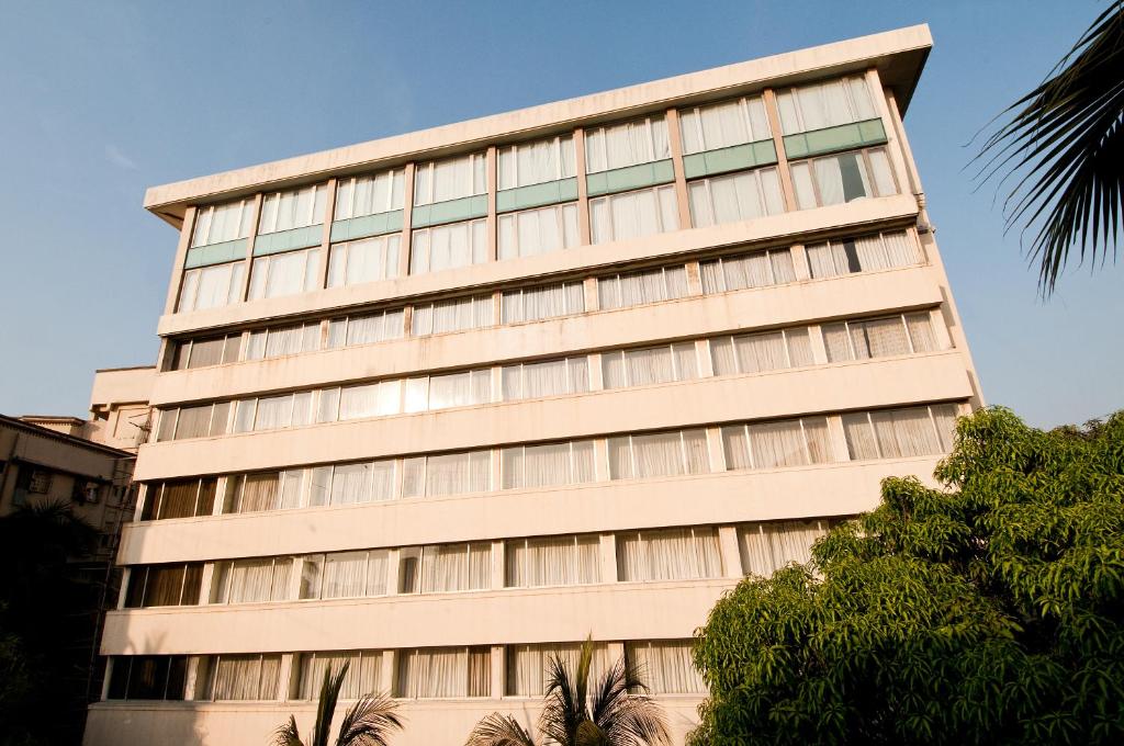 een hoog gebouw met bomen ervoor bij Hotel Residency Andheri in Mumbai