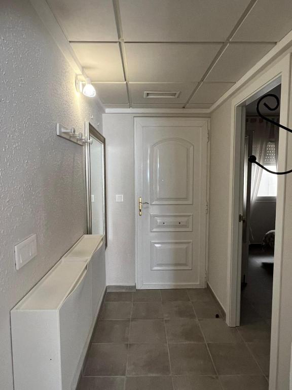 a white hallway with a mirror and a white door at Apartamentos La Mar in Altea