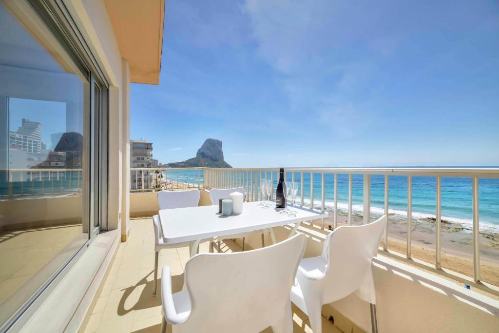 カルプにあるApartamento Capri - PlusHolidaysの白いテーブルと椅子、ビーチのあるバルコニー
