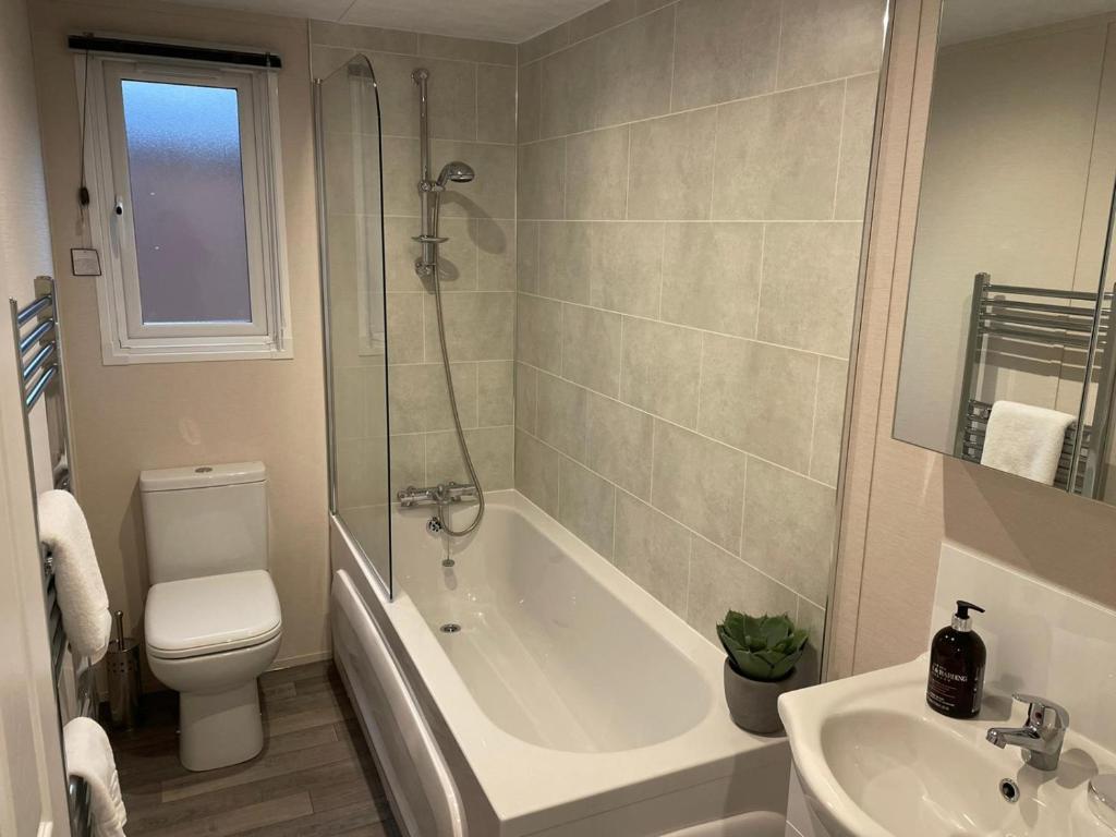 a bathroom with a tub and a toilet and a sink at Dakota Lodge with Hot Tub in York