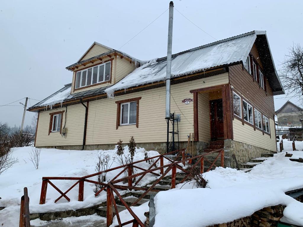 een huis met sneeuw op de grond ervoor bij Подина in Vorochta