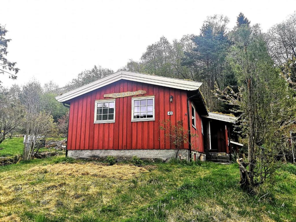 a red house on a hill in a field at Lysebakken, koselig feriehytte på Vestland in Reed