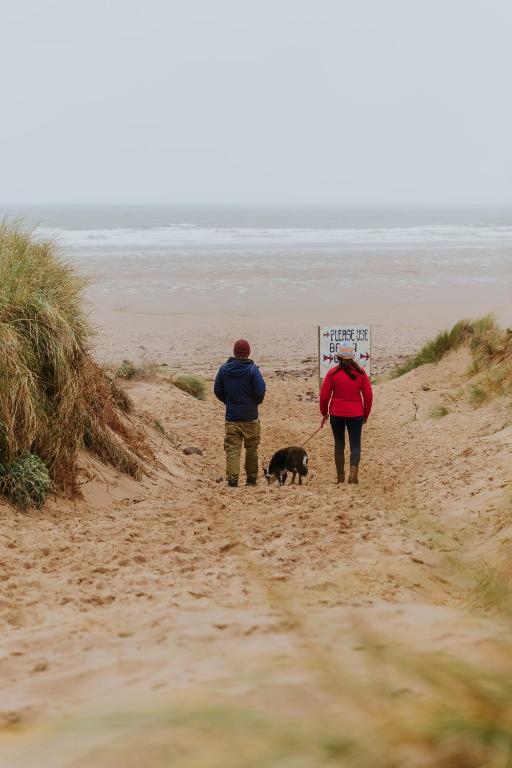 two people and a dog on a beach with a sign at King's Head Inn in Llangennith