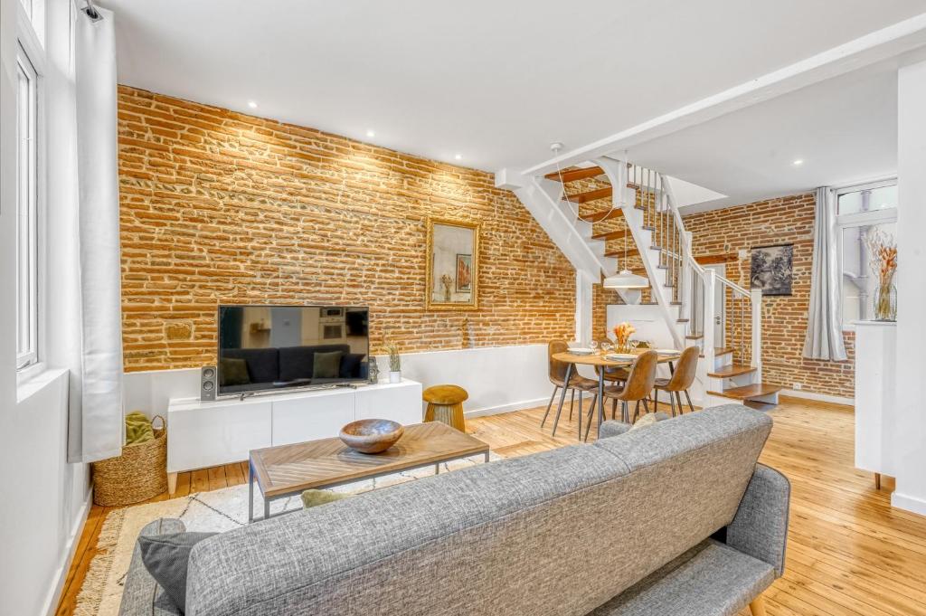 a living room with a couch and a brick wall at LE BROADWAY - Duplex entièrement rénové in Toulouse