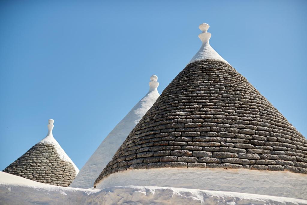 duas torres de um edifício com um céu azul no fundo em Petranima Wellness in Trulli em Ostuni