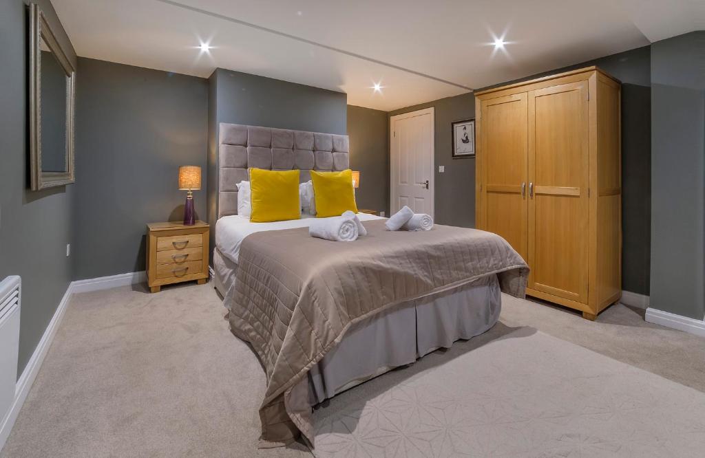 a bedroom with a large bed with yellow pillows at Gillygate Boutique Apartment- Stunning City Centre 1 Bedroom Apartment in York