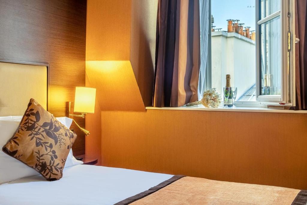 um quarto de hotel com uma cama e uma janela em Hotel Saint Honore 85 em Paris