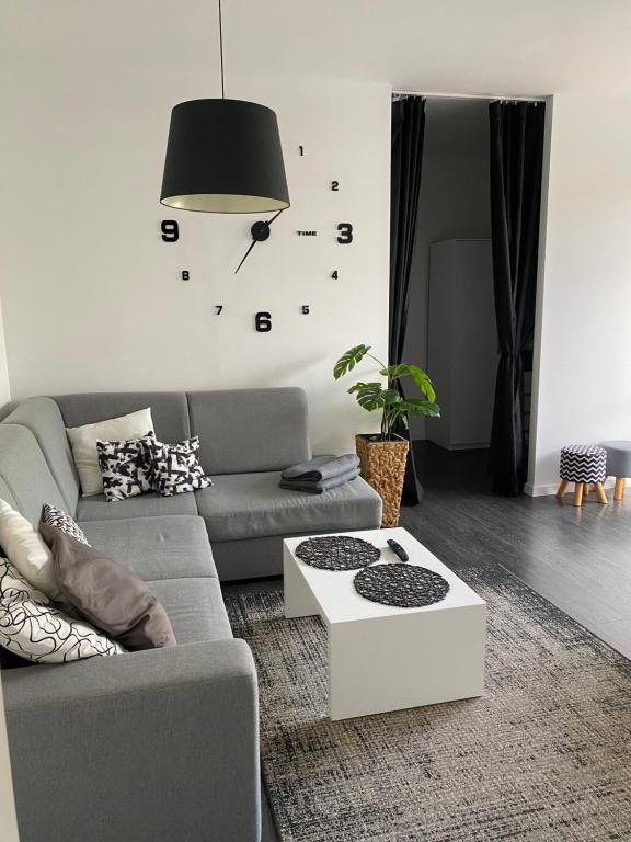 a living room with a couch and a clock on the wall at Apartament Kościuszki in Malbork