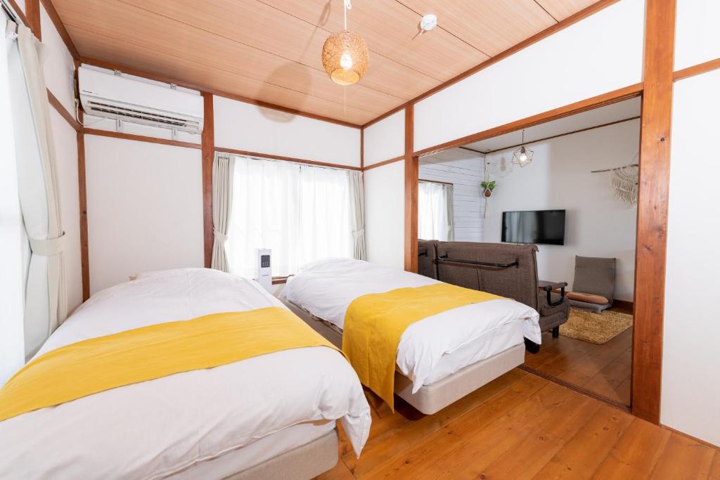 a bedroom with two beds and a television in it at Pine Tree in Kamakura