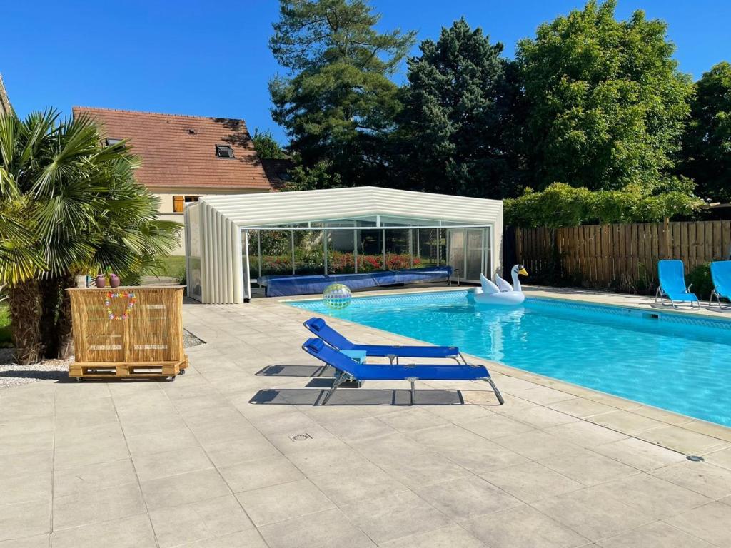 uma piscina com duas espreguiçadeiras azuis ao lado em L'Annexe- guest house avec piscine studio avec coin chambre em Rosny-sur-Seine