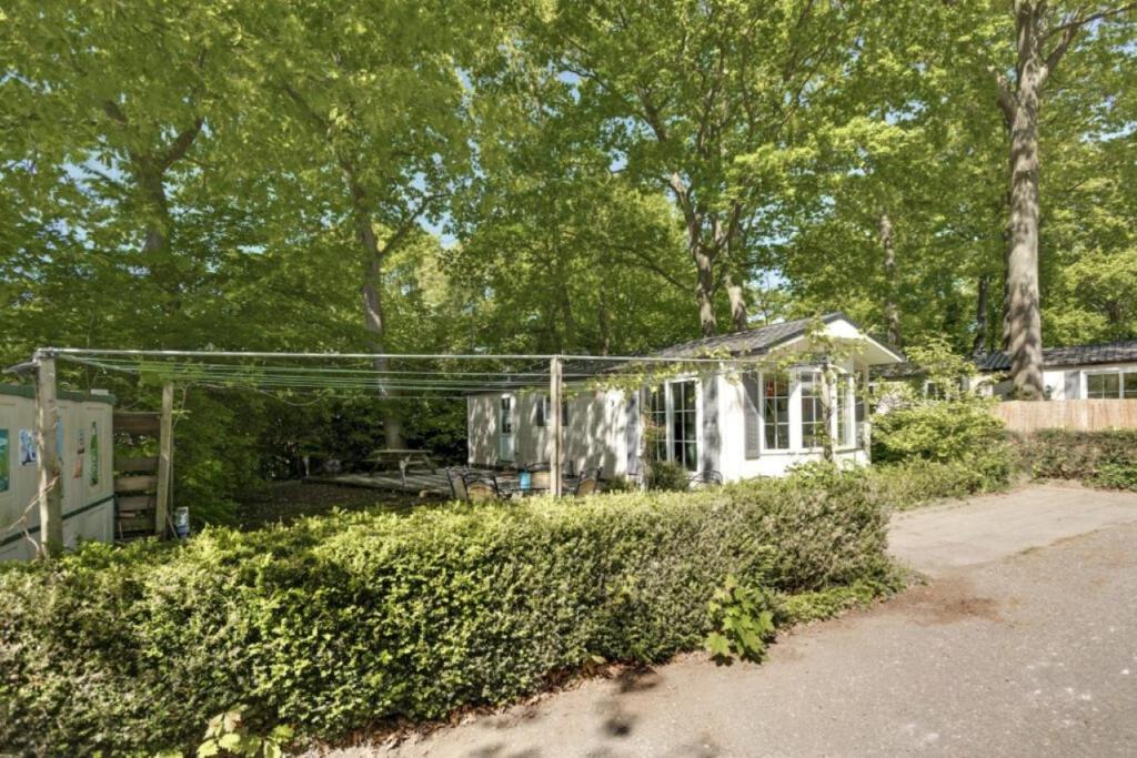 a small white house in a yard with trees at Boshuisje- Chez Michel in Wageningen