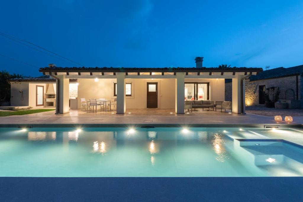 uma piscina em frente a uma casa à noite em Villa Angelina - IsulaTravel em Contrada Bosco