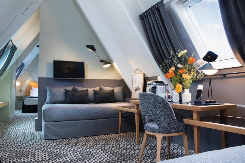 ein Wohnzimmer mit einem Sofa und einem Tisch in der Unterkunft Millésime Hôtel in Paris
