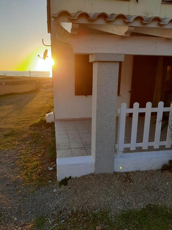 una recinzione bianca accanto a una casa con il tramonto di Nathan house Pistis a Torre Dei Corsari