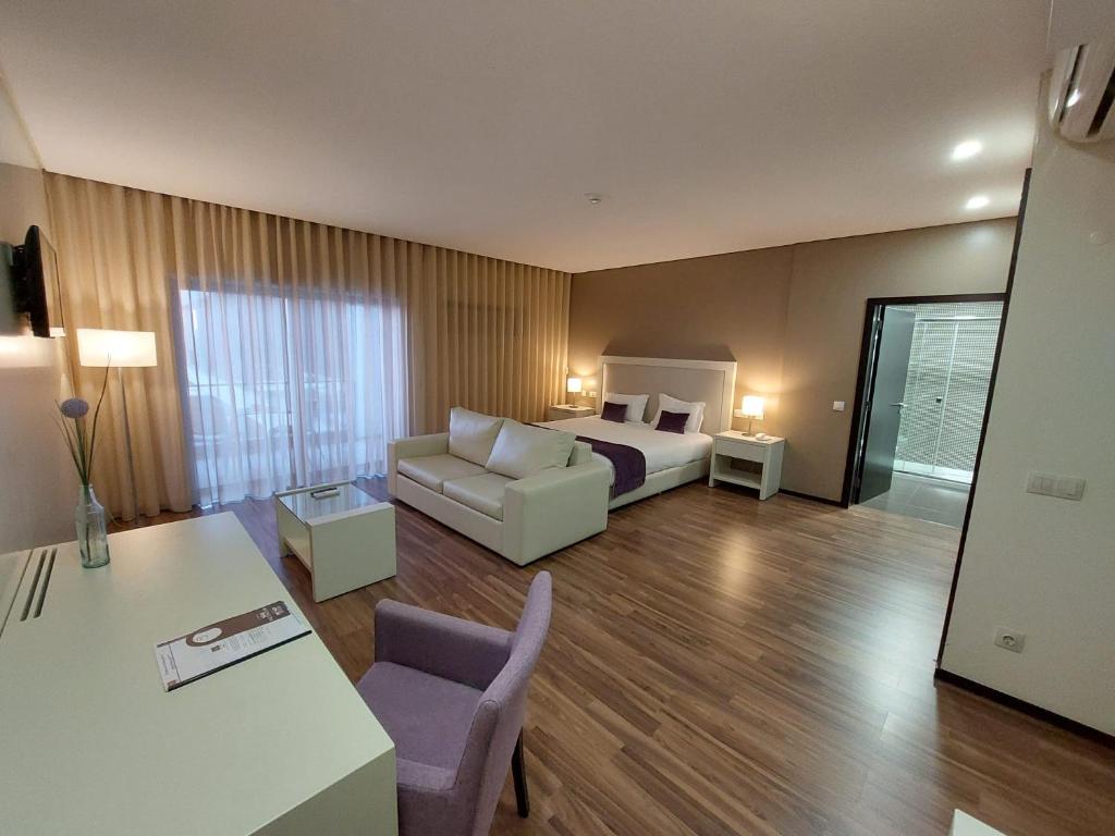 Habitación de hotel con cama y sofá en Hotel Monte Lírio en Espinho
