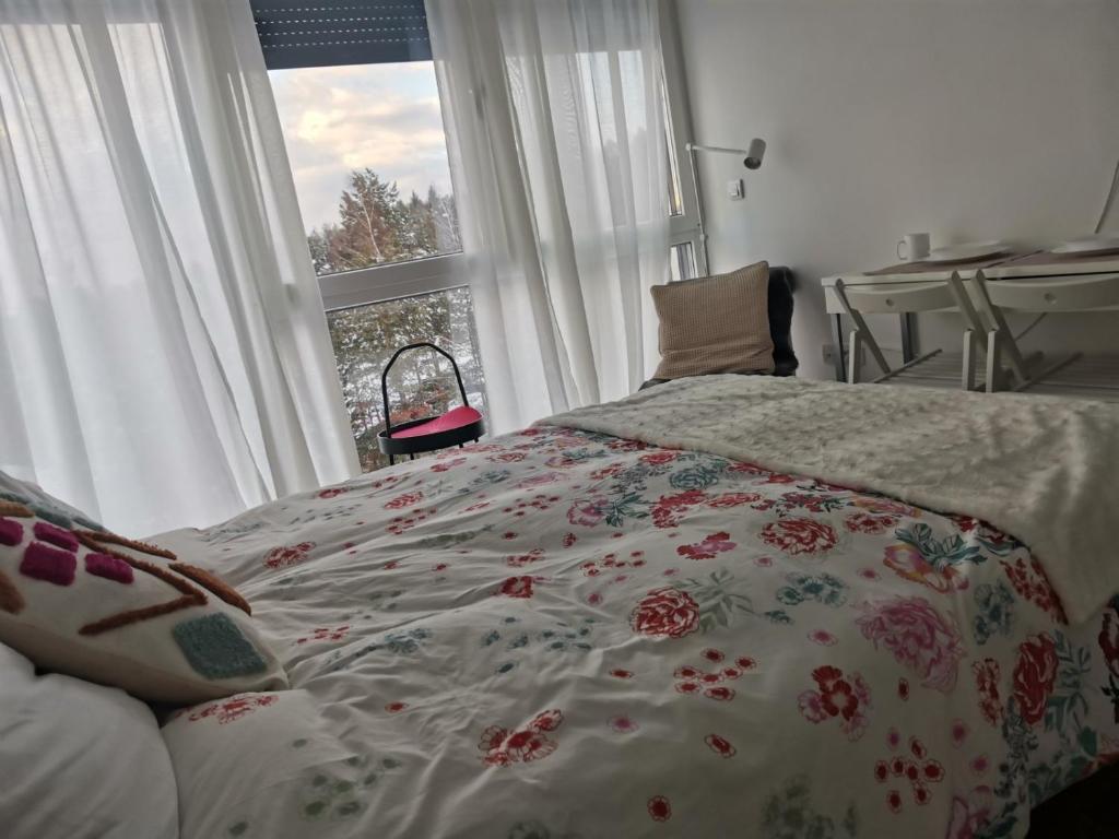 sypialnia z łóżkiem z kwiatową narzutą i oknem w obiekcie Divčibare Jezero apartman 25 w mieście Divčibare